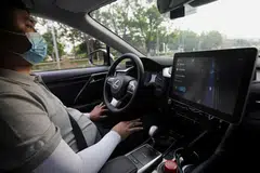 A safety driver monitors a Lexus vehicle equipped with Pony.ai's autonomous driving system as the car drives on a road during a test event, Beijing, China, May 13, 2021. Pony.ai plans to provide robotaxi commuting services for airport staff within Hong Kong International Airport before expanding into other urban areas in the city, the company said on Friday. 