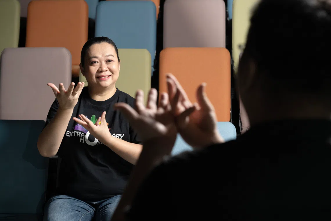 Deaf arts and music artiste Lily Goh signing “expression” in front of an interpreter.
