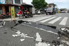 Vehicles manoeuvre past a damaged part of a road in Bogo City on Oct 1, 2025, after a powerful 6.9 magnitude earthquake jolted central Philippines, killing dozens on the island of Cebu with fears the toll could rise. 