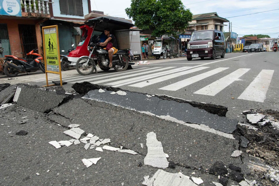 Vehicles manoeuvre past a damaged part of a road in Bogo City on Oct 1, 2025, after a powerful 6.9 magnitude earthquake jolted central Philippines, killing dozens on the island of Cebu with fears the toll could rise. 