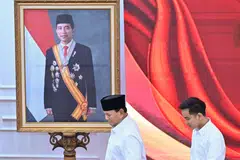 Indonesian president-elect Prabowo Subianto (left) and vice-president-elect Gibran Rakabuming Raka walk past a picture of Gibran's father, President Joko Widodo, at an event in Jakarta.