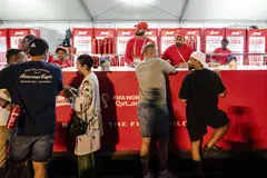 People purchasing beer from a Budweiser tent at a fan zone. A bottle of beer there is nearly 10 times the price of what it costs at a convenience store in South Korea.
