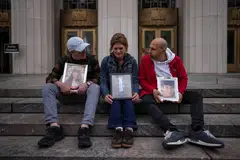 (From left) Mariano Janin, Ellen Roome, and George Nicolaou sit outside a court with photos of their children who died, during a trial in a key test case accusing Meta and Google's YouTube of harming children's mental health through addictive platforms, Los Angeles, California, Feb 11, 2026. 