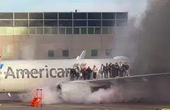 Passengers standing on the wing of an American Airlines plane as they are evacuated after it caught fire while at a gate at Denver International Airport in Denver, Colorado, March 13, 2025. 
