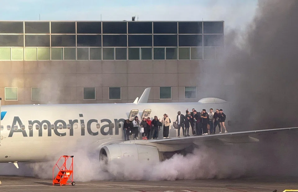 Passengers standing on the wing of an American Airlines plane as they are evacuated after it caught fire while at a gate at Denver International Airport in Denver, Colorado, March 13, 2025. 