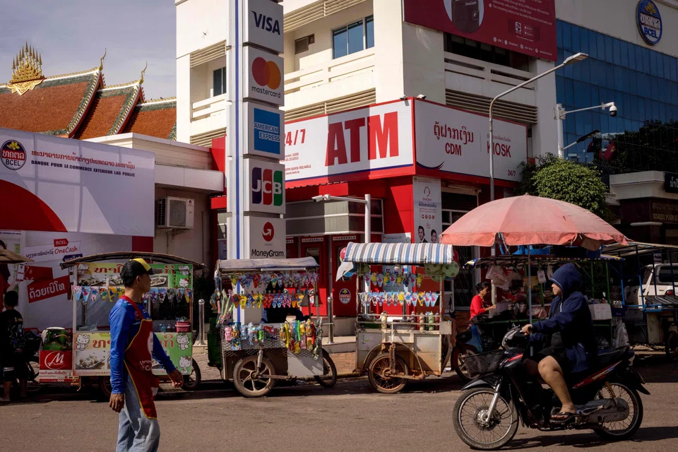 Street vendors sell their wares in front of an ATM in Vientiane, Laos. The IMF estimates the country's public debt to be 122 per cent of GDP in 2023.
