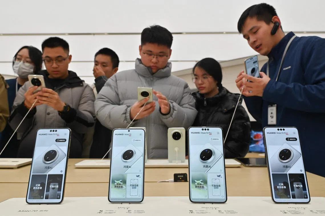 People check Huawei's new Mate 70 mobile phone at a shop at the Wangfujing shopping area in Beijing, China, Nov 26, 2024. 