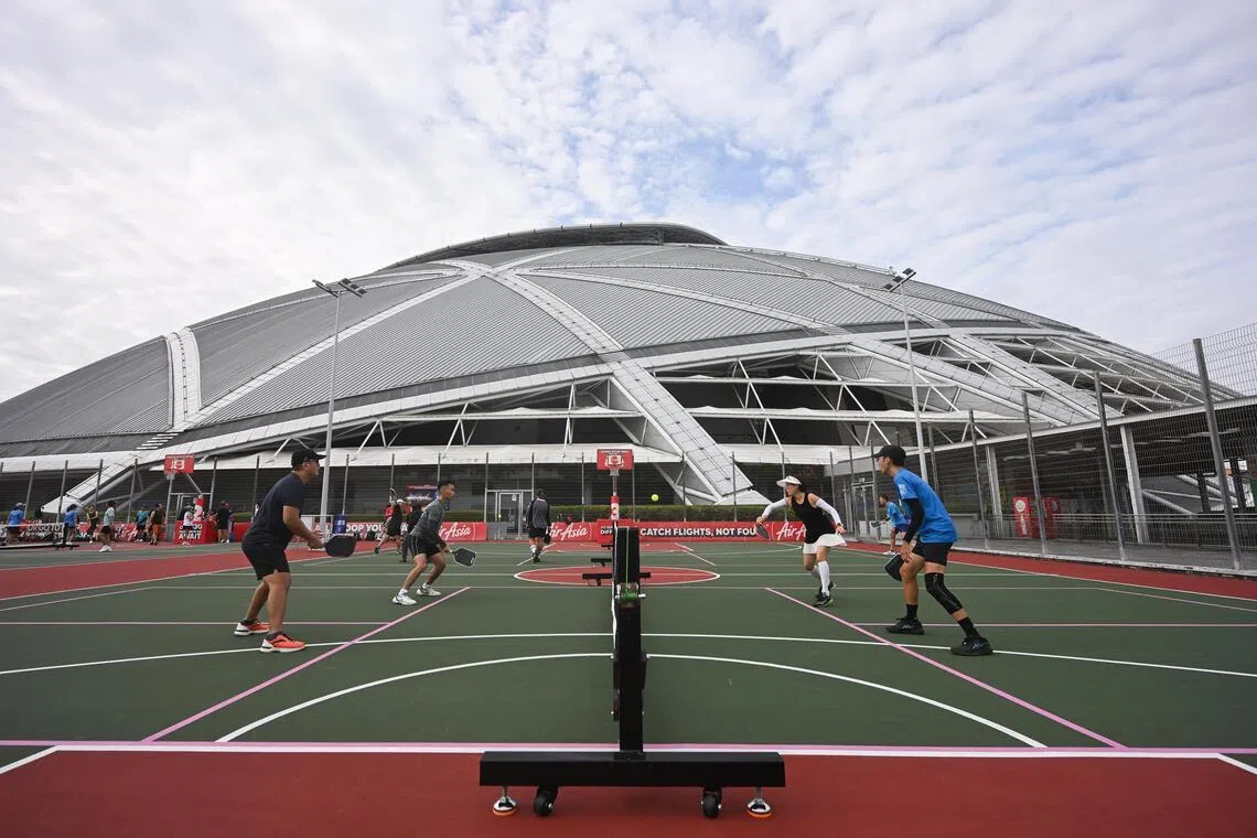 Pickleball players enjoying a match at the newly opened dual-use courts at The Kallang, with the National Stadium in the background.