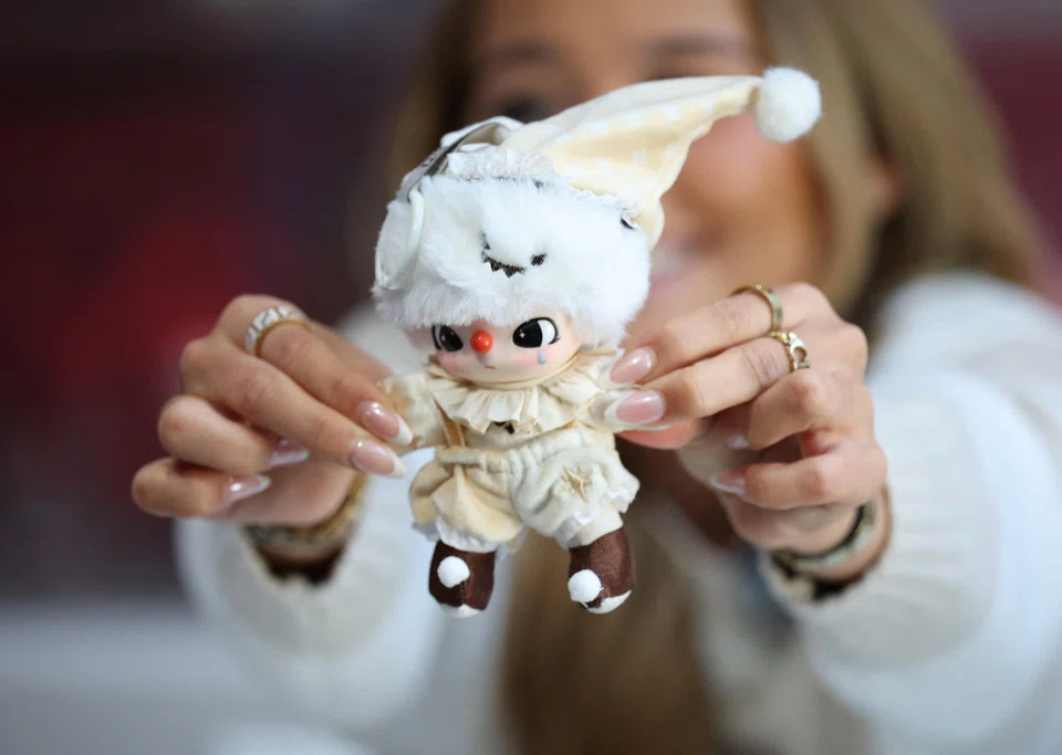 An influencer holds a Labubu Why So Serious Plush Pendant doll during an AliExpress and Pop Mart livestream shopping show on Singles' Day at a pop-up store in London on Nov 11.