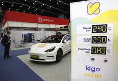 An electric car on display at a recent trade show in Bangkok, next to a board that shows the price of using electricity compared to petrol and diesel. Thailand is rolling out incentives to encourage the manufacturing of EVs in the country.