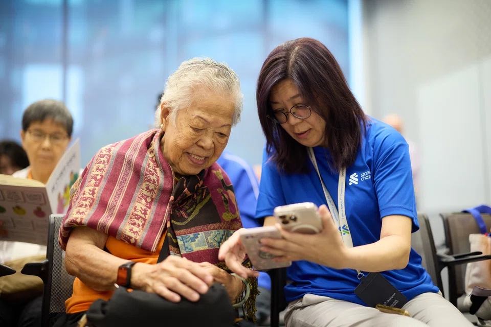 A StanChart volunteer guiding a senior during a fraud prevention workshop in January.