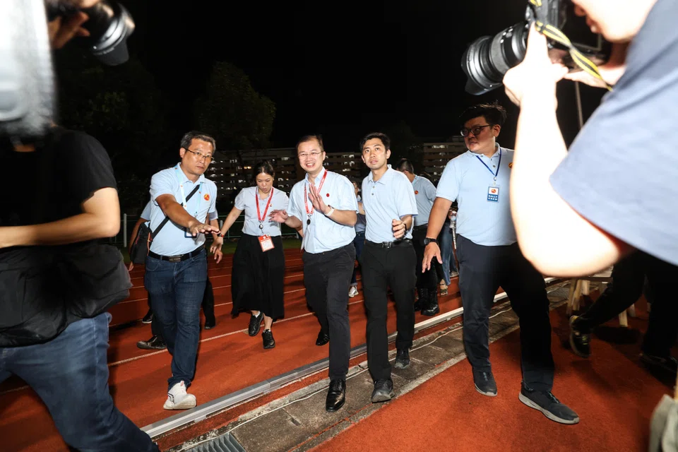 Workers' Party's Louis Chua (centre) and He Ting Ru (second from left) entering Serangoon Stadium on May 3.