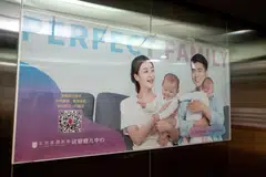 An advertisement featuring an image of a family, in an elevator at Beijing Perfect Family Hospital. With fewer babies and more deaths, policymakers are facing a demographic crisis in the making. 