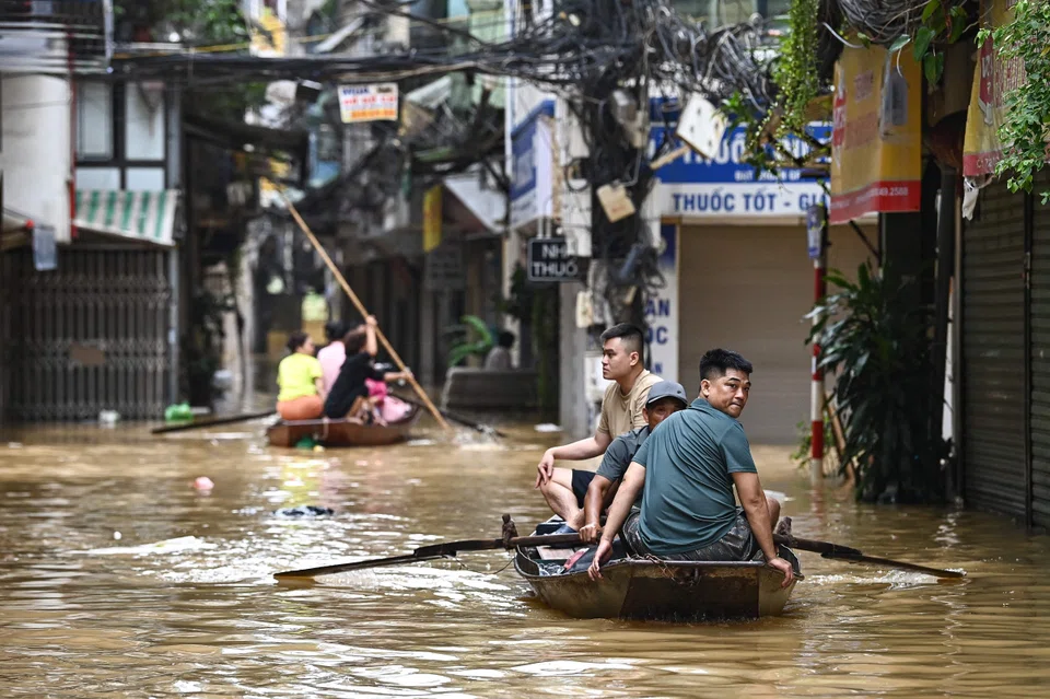 People wade through flood waters on a boat in Hanoi as heavy rains in the aftermath of Typhoon Yagi brought flooding to northern Vietnam.