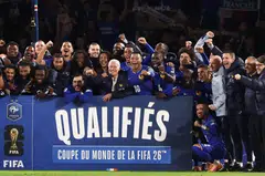 French forward Kylian Mbappe (wearing #10) with head coach Didier Deschamps (to his right) and other players as they celebrate France's qualification for next year's World Cup.