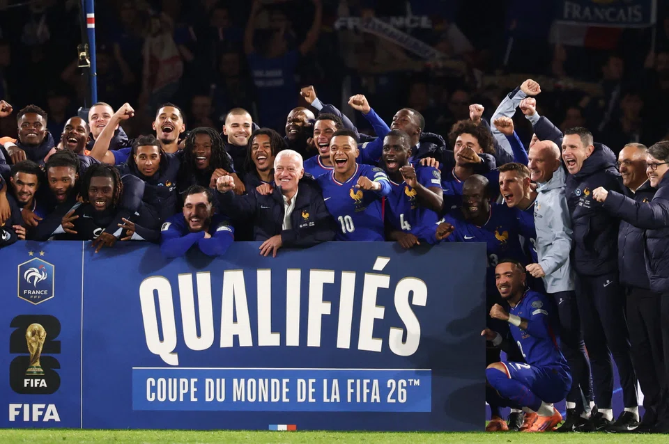 French forward Kylian Mbappe (wearing #10) with head coach Didier Deschamps (to his right) and other players as they celebrate France's qualification for next year's World Cup.
