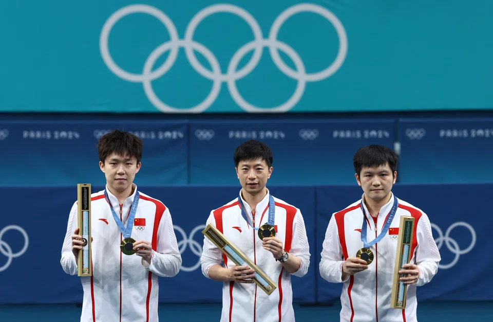 Gold medallists team of China, from left, Wang Chuqin, Ma Long and Fan Zhendong celebrate on the podium after winning men’s table tennis team event in Paris. 