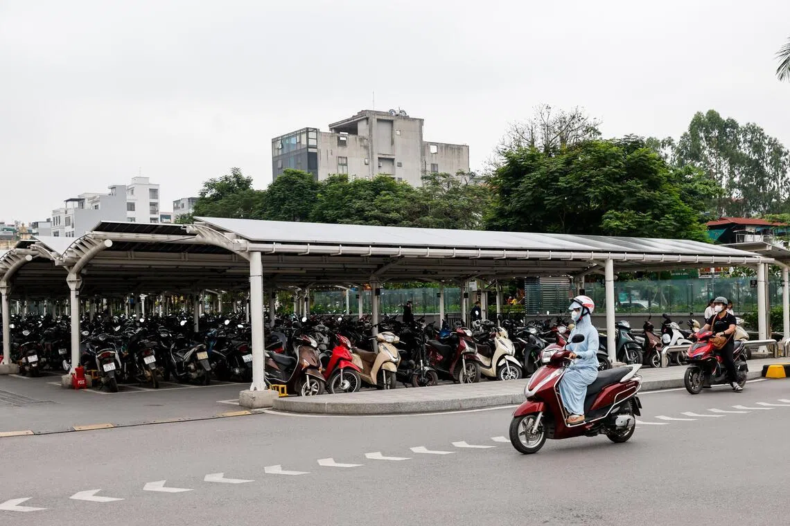 epa12903700 A woman rides motorbike past a parking area in Hanoi, Vietnam 21 April 2026. Earth Day is celebrated annually on 22 April, with the 2026 theme being 'Our Power, Our Planet'.  EPA/LUONG THAI LINH