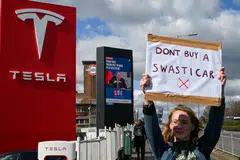 A demonstrator holds an anti-Tesla poster during a protest encouraging people to boycott Tesla, outside the Tesla Centre Park Royal in London, Britain, March 15, 2025. 