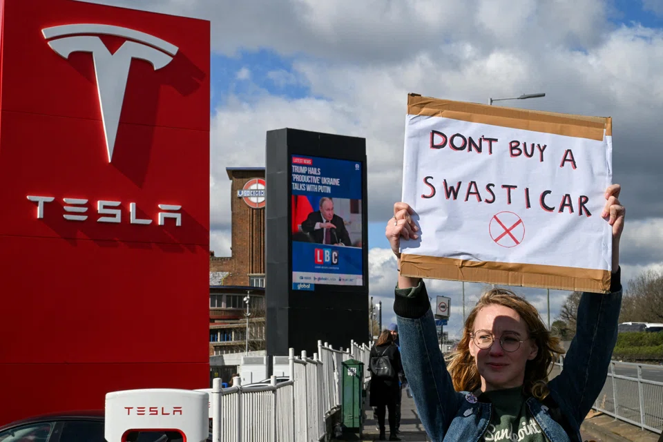 A demonstrator holds an anti-Tesla poster during a protest encouraging people to boycott Tesla, outside the Tesla Centre Park Royal in London, Britain, March 15, 2025. 