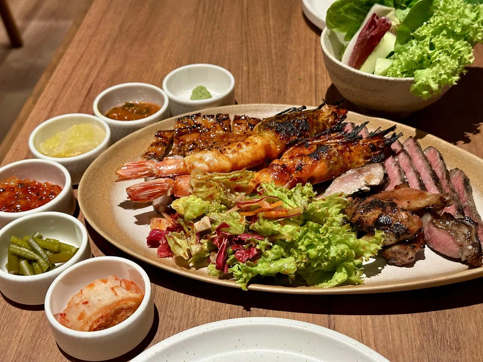 Grilled platter of meat and seafood with accompaniments.