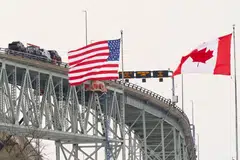 United States and Canadian flags fly on the US side of the St. Clair River near the Bluewater Bridge border crossing between Sarnia, Ontario and Port Huron, Michigan on Jan 29, 2025. US President Donald Trump's sweeping tariffs on Canada and Mexico are set to roil supply chains for products ranging from automobiles to avocados - with industries girding for cost increases.