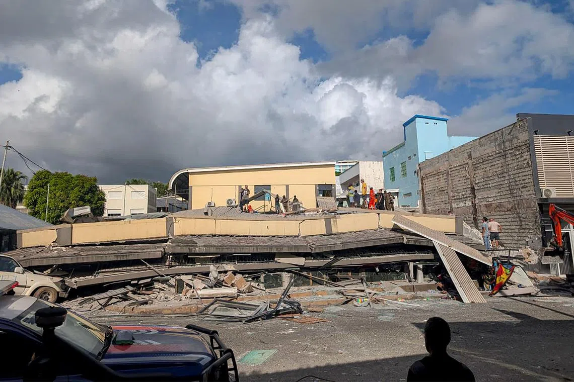 Rescue workers are seen at the site of a collapsed building after a powerful earthquake struck Port Vila, the capital city of Vanuatu.