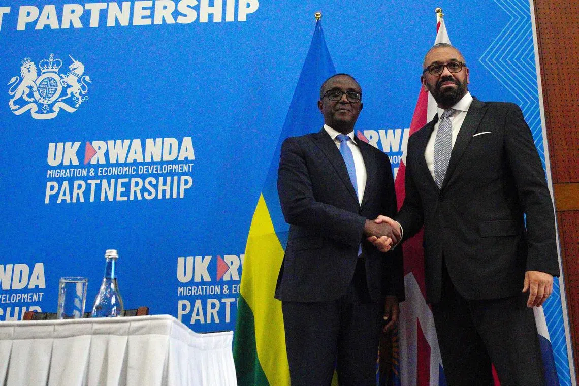 Britain's Home Secretary James Cleverly (R) and Rwanda's Foreign Minister Vincent Biruta shake hands after signing a new treaty to revive a controversial proposal by London to transfer migrants to the east African country. 
