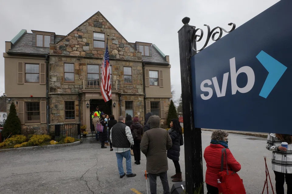 Customers wait in line outside a branch of the Silicon Valley Bank in Wellesley, Massachusetts, US, March 13, 2023.     