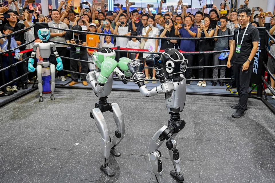 People watch humanoid robots boxing at an exhibition during the World Artificial Intelligence Conference in Shanghai on Jul 26.