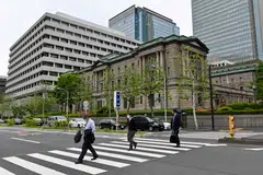 Pedestrians walk in front of the Bank of Japan head office building in Tokyo. Financial leaders from Japan, China and South Korea urged caution against heightening risks.
