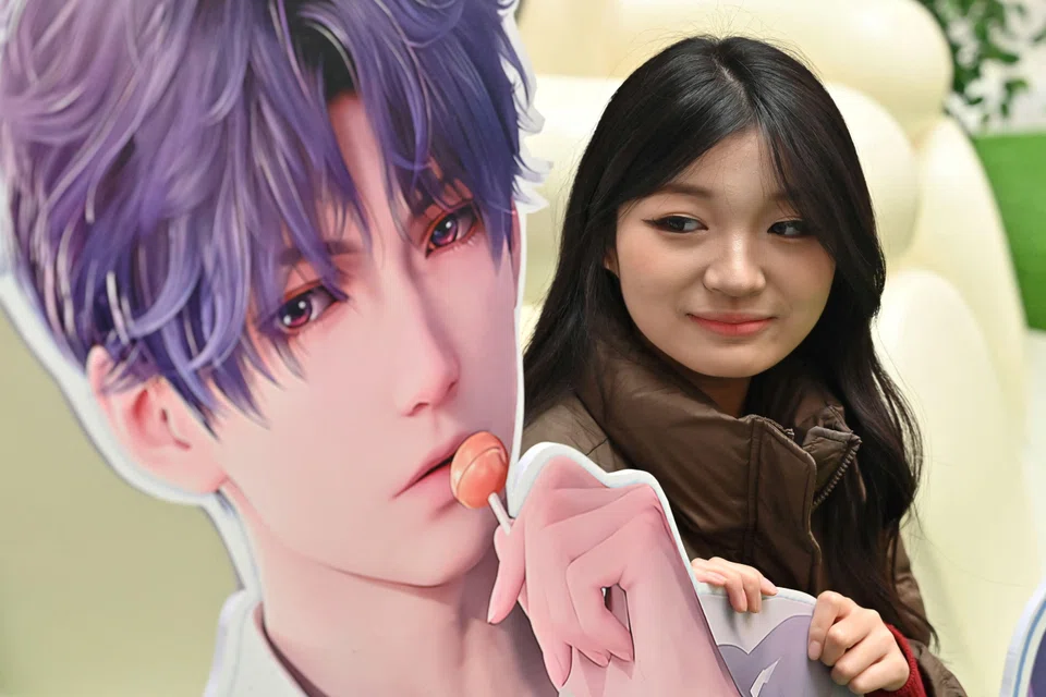 A woman poses during a birthday celebration event for Rafayel, a virtual character in the romantic mobile game "Love and Deepspace" at a shopping mall in Beijing.