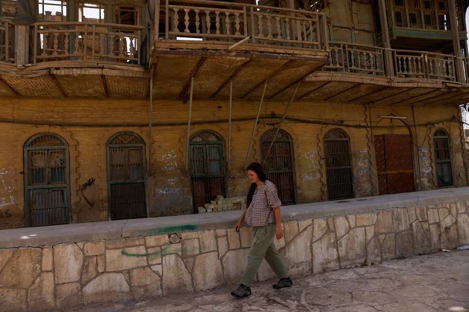 Dhikra Sarsam, a founding member of the Burj Babel Initiative to protect heritage, walks in front of one of Baghdad's remaining heritage homes.