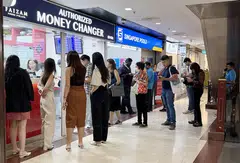Customers checking out foreign exchange rates at money changers in The Arcade.  