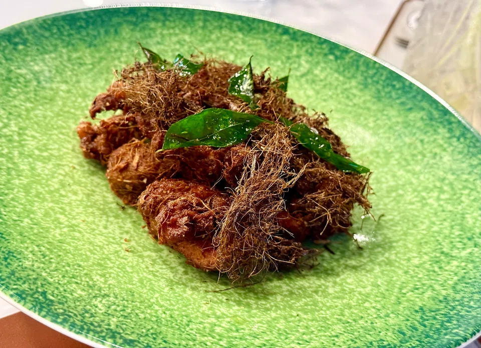 Finely shredded herbs top the ayam goreng berempah.