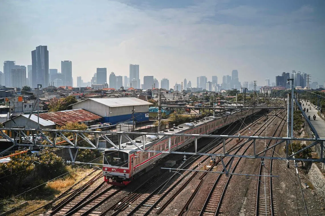 A passenger train glides on the tracks in downtown Jakarta on November 5, 2024. (Photo by BAY ISMOYO / AFP)