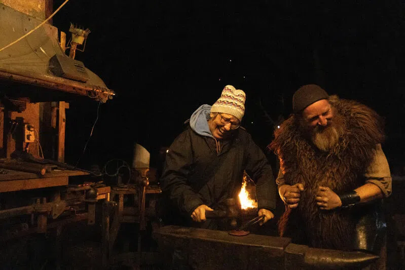 Ironmonger Tom King, also known as 'An Gobha', cheers as tourist Darlene Molitor, 67, from Minnesota in the US, tries her hand at hammering metal in his forge.