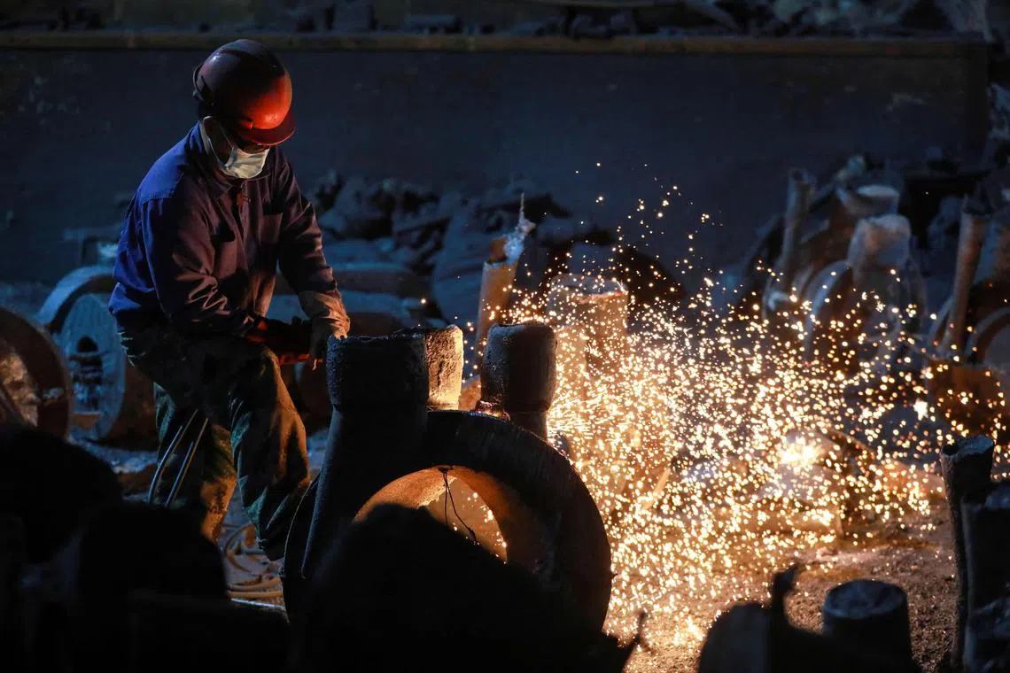 A worker polishes machinery in the workshop of a factory which produces steel machinery for export, in Hangzhou, in China’s eastern Zhejiang province on February 21, 2025. (Photo by AFP) / China OUT