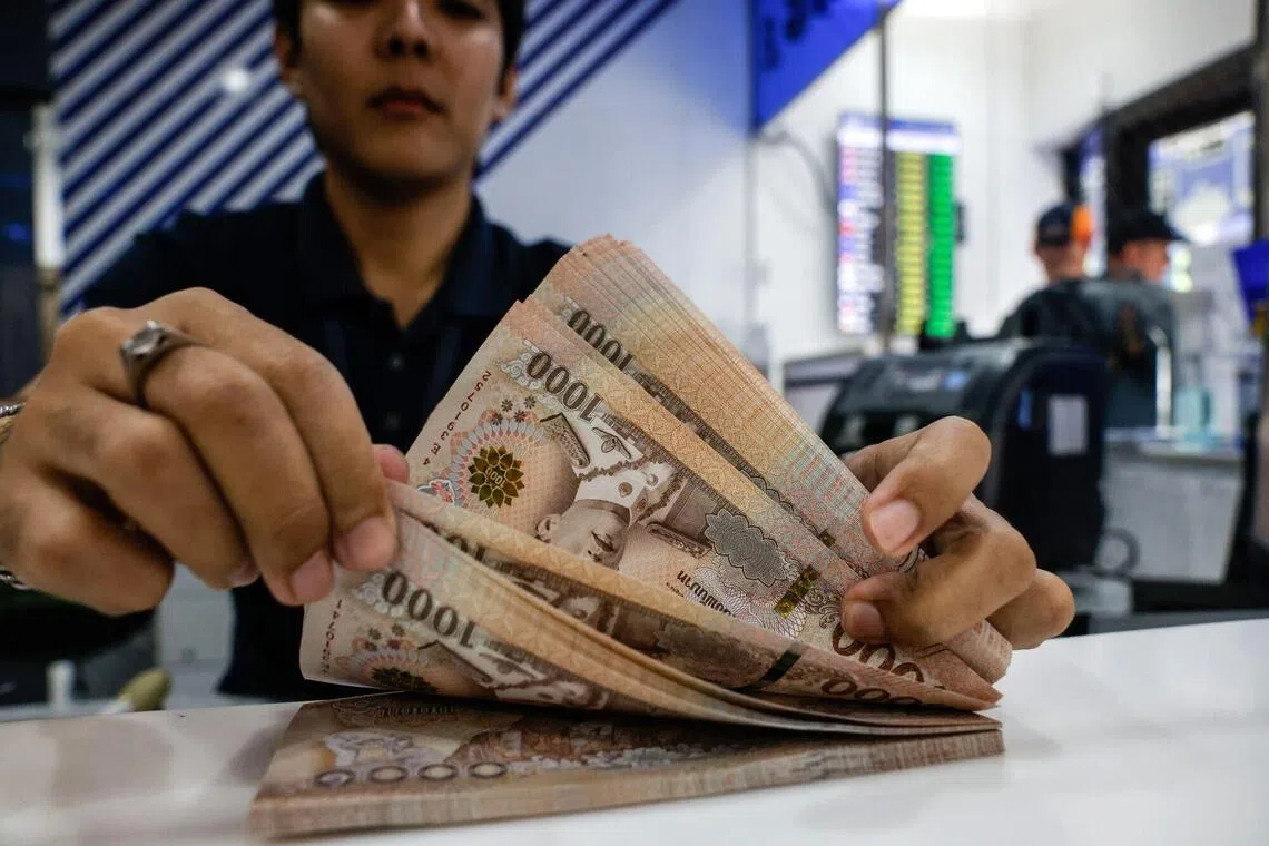 An employee counts 1,000 baht banknotes at a Siam Exchange store in Bangkok, Thailand, on Thursday, Sept. 25, 2025. Thailand will take all possible measures to avert a sovereign credit rating downgrade, Prime Minister Anutin Charnvirakul said, a day after Fitch Ratings lowered the nation's outlook citing rising risks to public finance. Photographer: Dario Pignatelli/Bloomberg