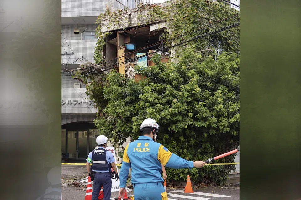 Police officers stand guard near a building damaged following an earthquake in Miyazaki, southwestern Japan.