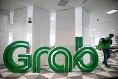 A GrabFood delivery man walking past the company logo in the new Grab office at Marina One West Tower on May 28, 2018. Ride-hailing app Grab holds a media briefing to share about its plans and direction. 