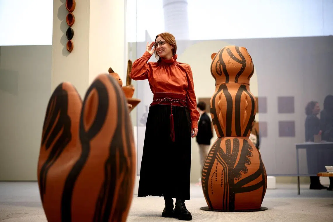Venezuelan artist Lucia Pizzani poses beside a ceramic artwork displayed as part of her exhibition "Smoke" during the Frieze Art Fair at Regent's Park in London.