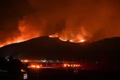 Red glowing flames and smoke rise from the Hughes Fire in north-west Los Angeles County, California, on Jan 22. JPMorgan estimates that the economic cost of the LA wildfires will total around US$50 billion. However, only US$20 billion of this will be insured.