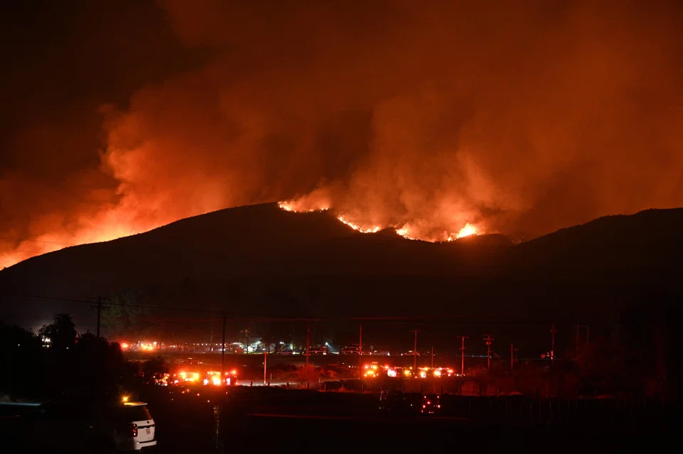 Red glowing flames and smoke rise from the Hughes Fire in north-west Los Angeles County, California, on Jan 22. JPMorgan estimates that the economic cost of the LA wildfires will total around US$50 billion. However, only US$20 billion of this will be insured.