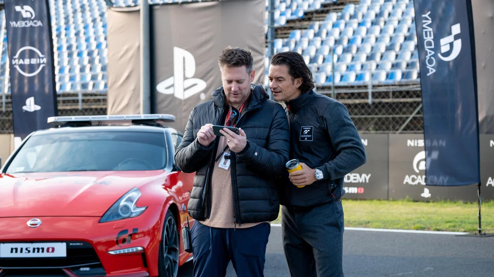 Gran Turismo's director Neil Blomkamp (left) directs a cast that includes Lord of the Rings star Orlando Bloom (right) and Stranger Things actor David Harbour.