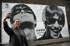 A fan takes a photograph with a mural depicting Oasis' Liam and Noel Gallagher on the side of Sifters Records in Manchester, Britain, Aug 27, 2024.