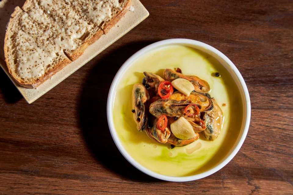 Pickled mussels in a flavoured brine are served with toast on the side.