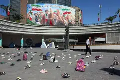 Symbolic belongings of Minab schoolgirls killed in a US airstrike were laid on the floor at Valiasr Square in Teheran on Apr 22, in front of a huge poster of the late Iranian supreme leader Ayatollah Ali Khamenei.