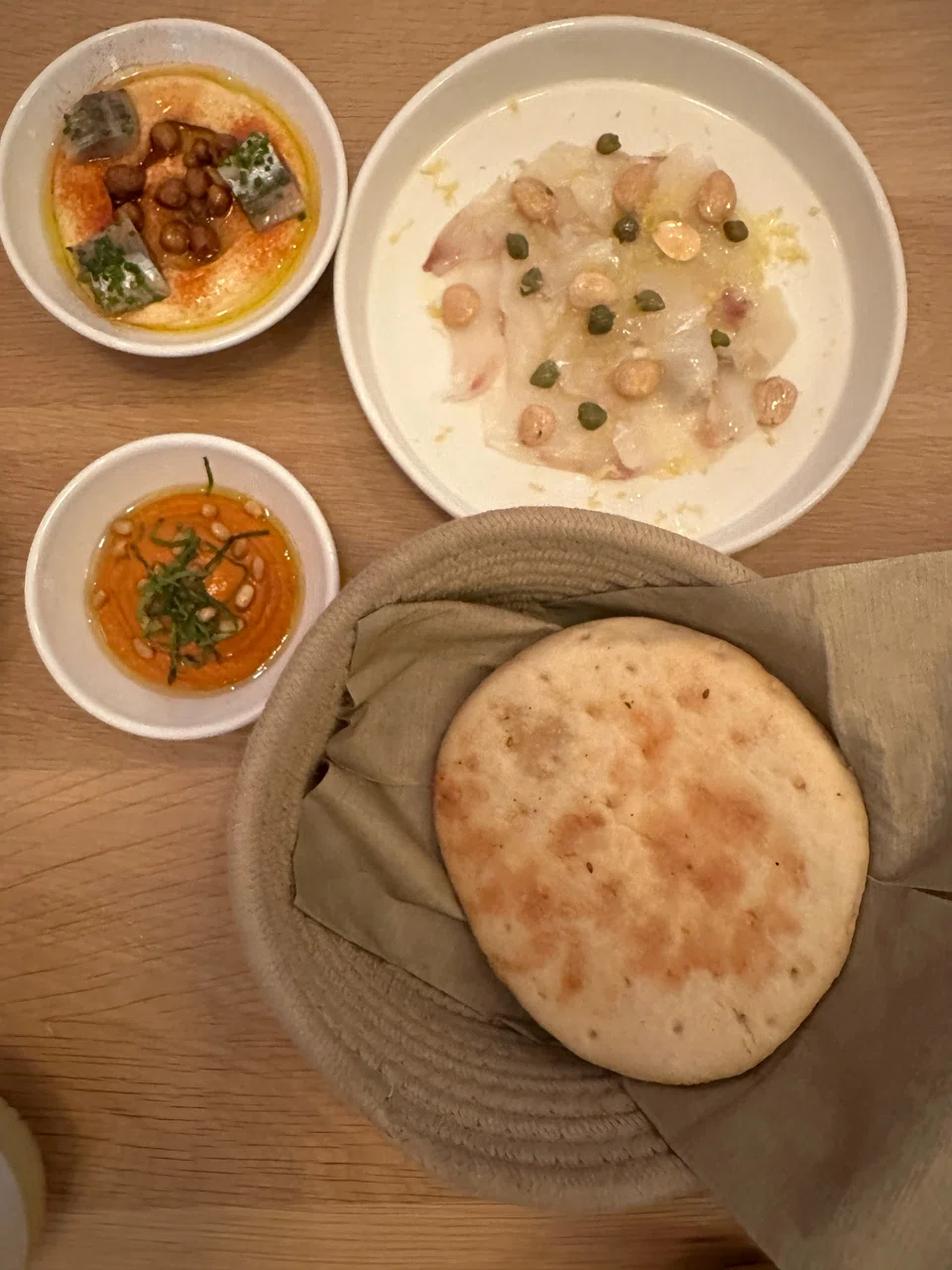 Noa's appetisers feature muhamarra, smoked sea bass carpaccio, hummus and pita.