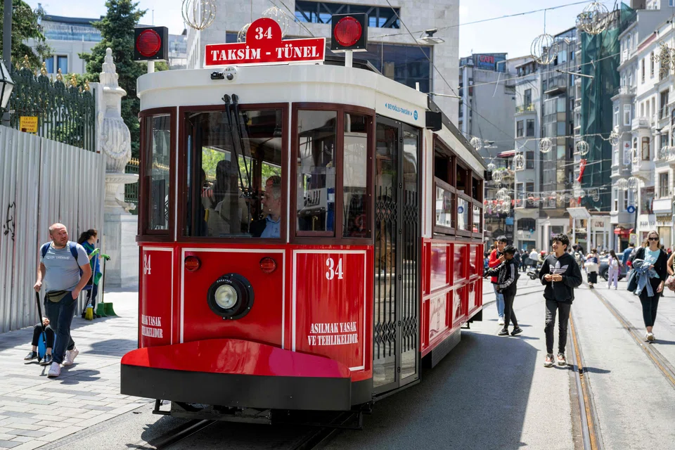 A modern battery-powered electric iconic red and white tram on rails plying Istiklal Avenue in Istanbul. The tram can run for two days on a single battery.